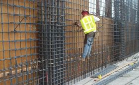 A man dressed in safety gear scales a metal wall