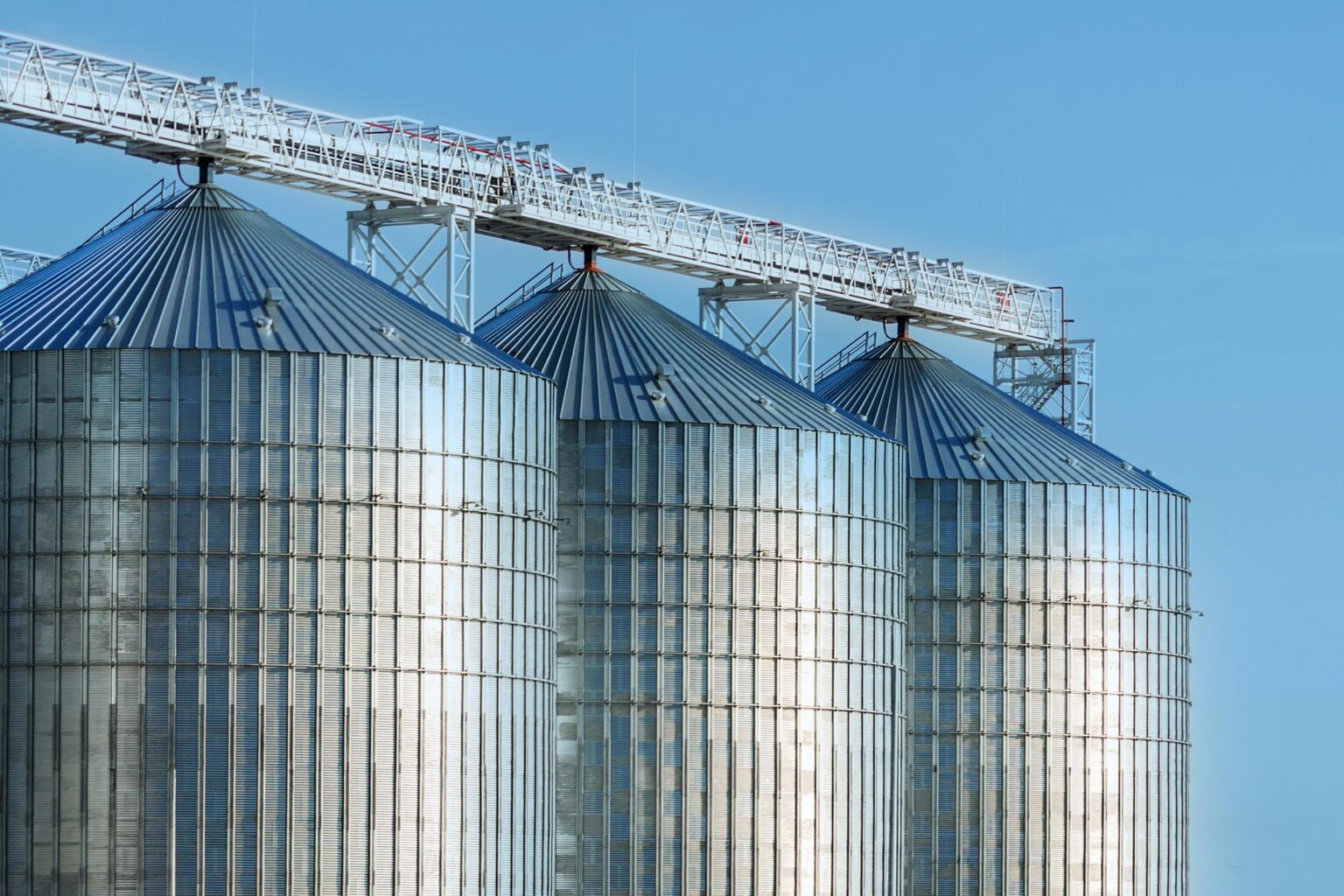 Modern agricultural silos or grain elevator with blue sky on the background. Storage of grain and other different cereals.