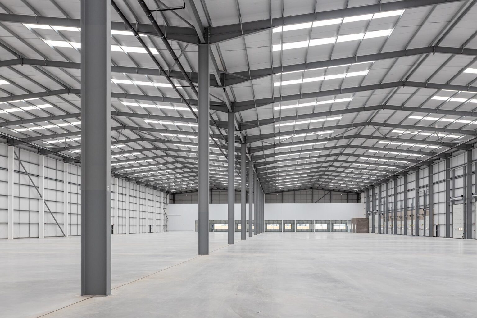 An interior of a large empty warehouse with overhead lights on
