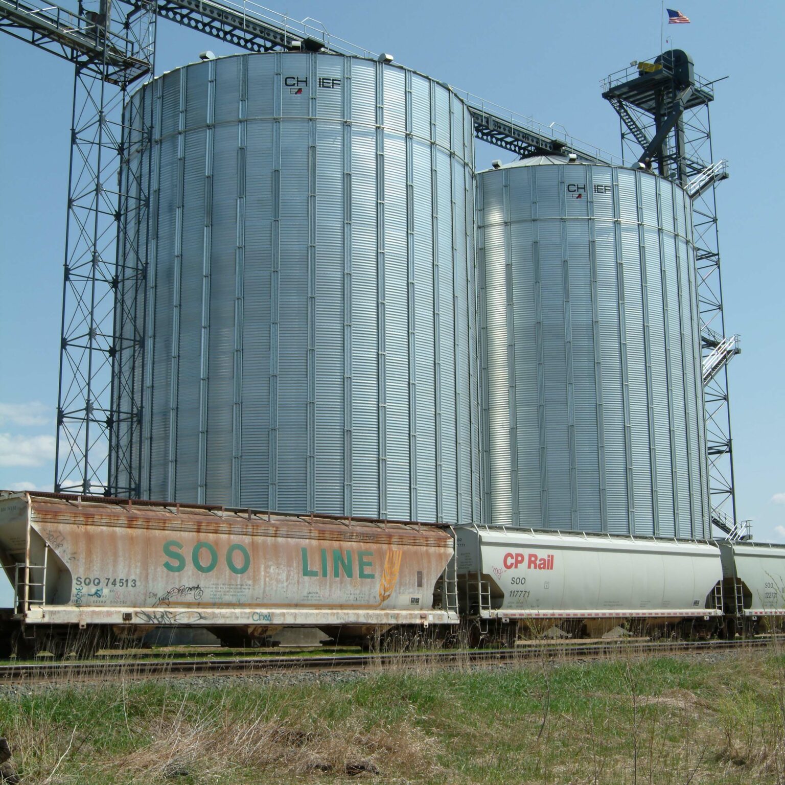 Exterior view of twin steel buildings with a train in the foreground