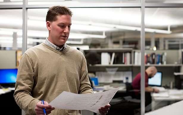 Profile photo of a man in a sweater reviewing a sheet of paper