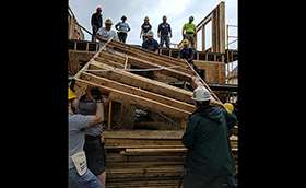 Action shot of a group of volunteers assembling a new house