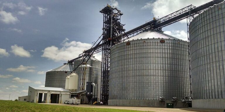 Wide exterior shot of a farm facility featuring large steel silos