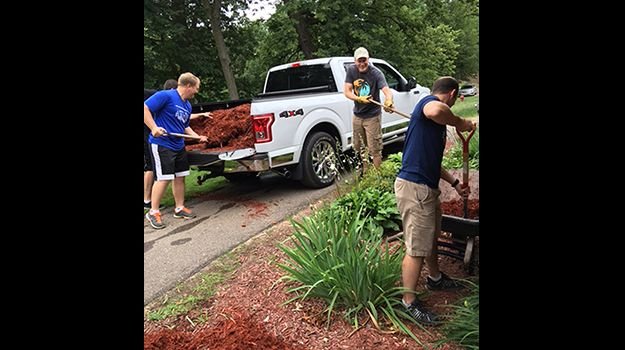 A group of volunteers spread mulch around some landscaping