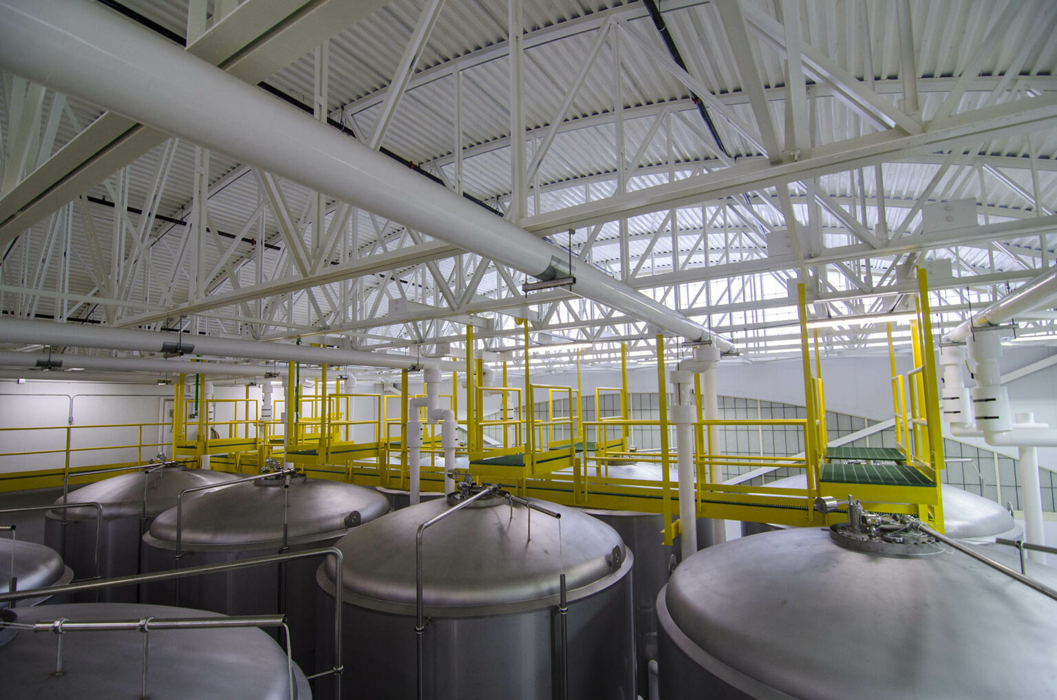 Interior view of a brewery's stills with a yellow walking plank