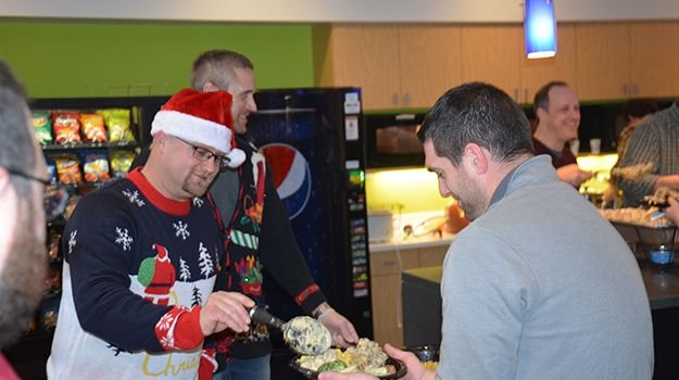 Candid photo of a man in a Santa hat serving food to another man