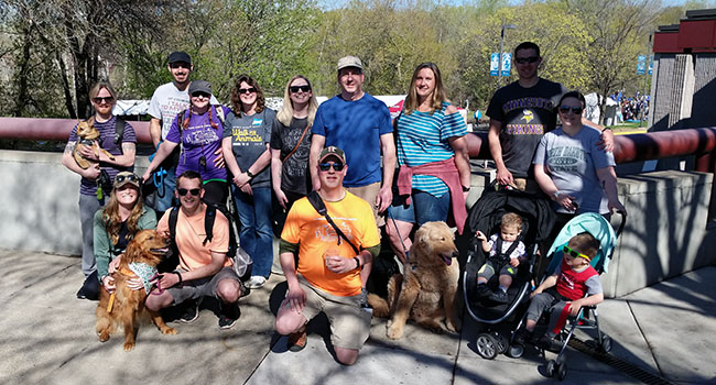 A group of volunteers gather outdoors in casual clothing with their dogs