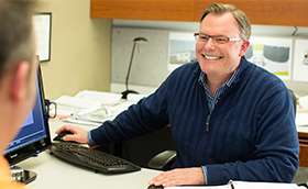 Candid photo of a man behind a desk smiling