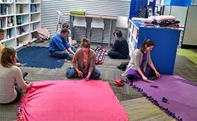 Photo of volunteers on the floor tying blankets