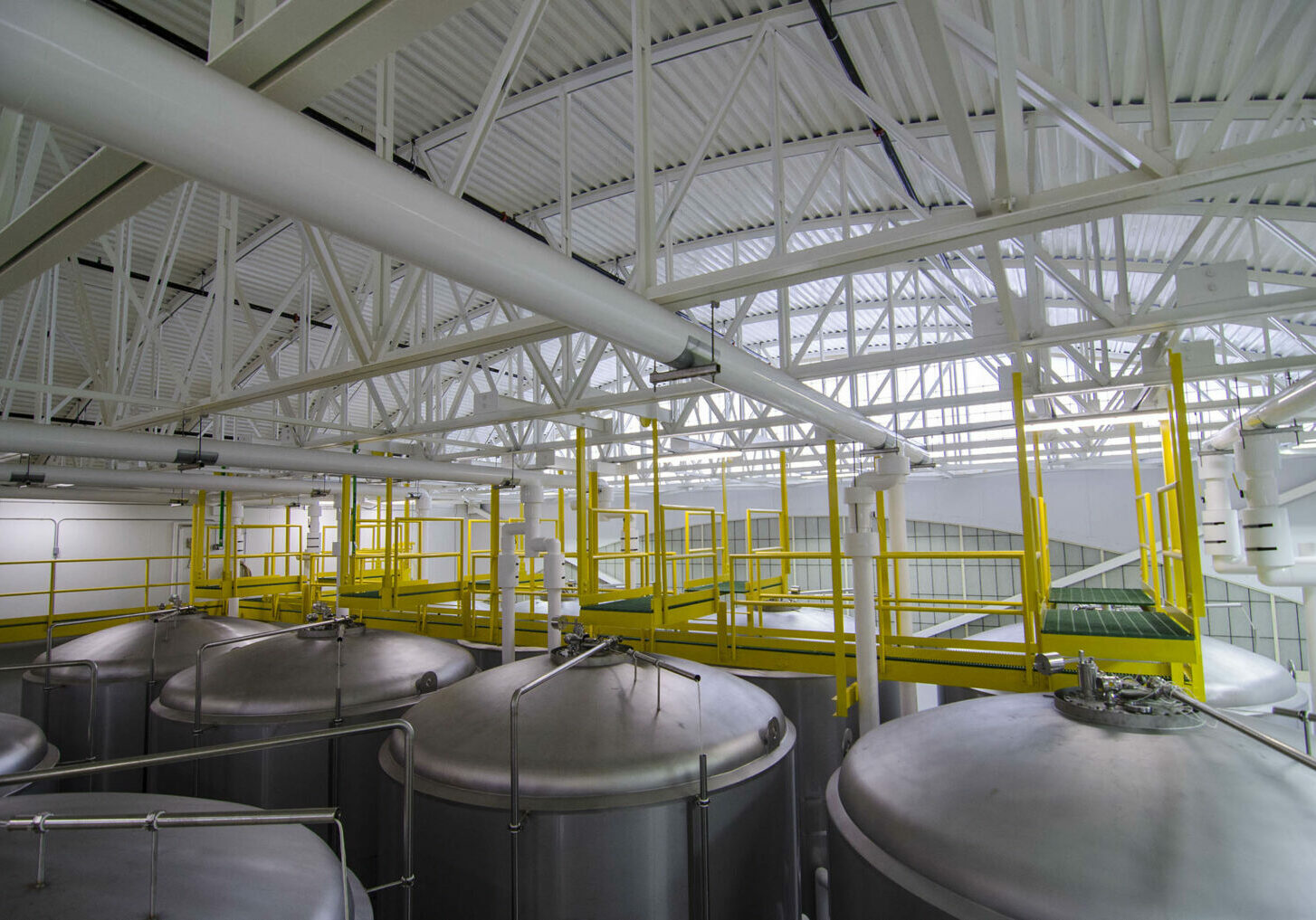Interior view of a brewery's stills with a yellow walking plank